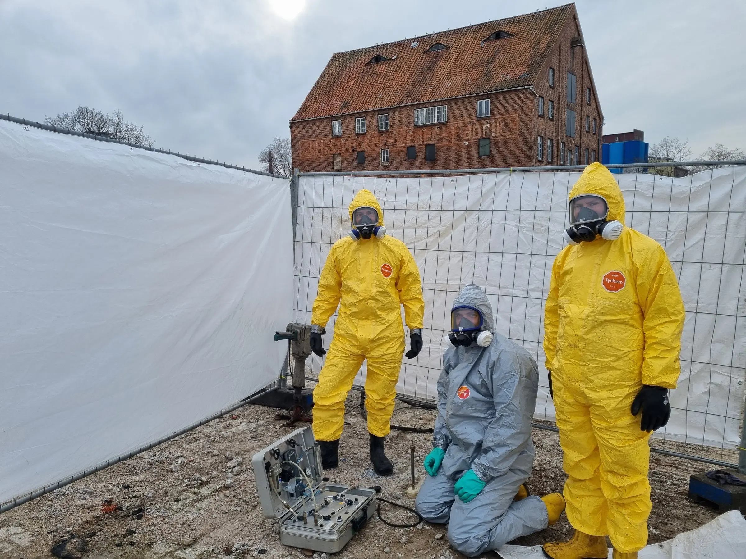 Team in Chemikalienschutzanzügen bei einer Altlastenerkundung auf einem Industriegelände